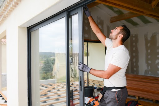 handsome young man installing bay window in a new house construction site Bouwbedrijf voor verbouwingen en renovaties